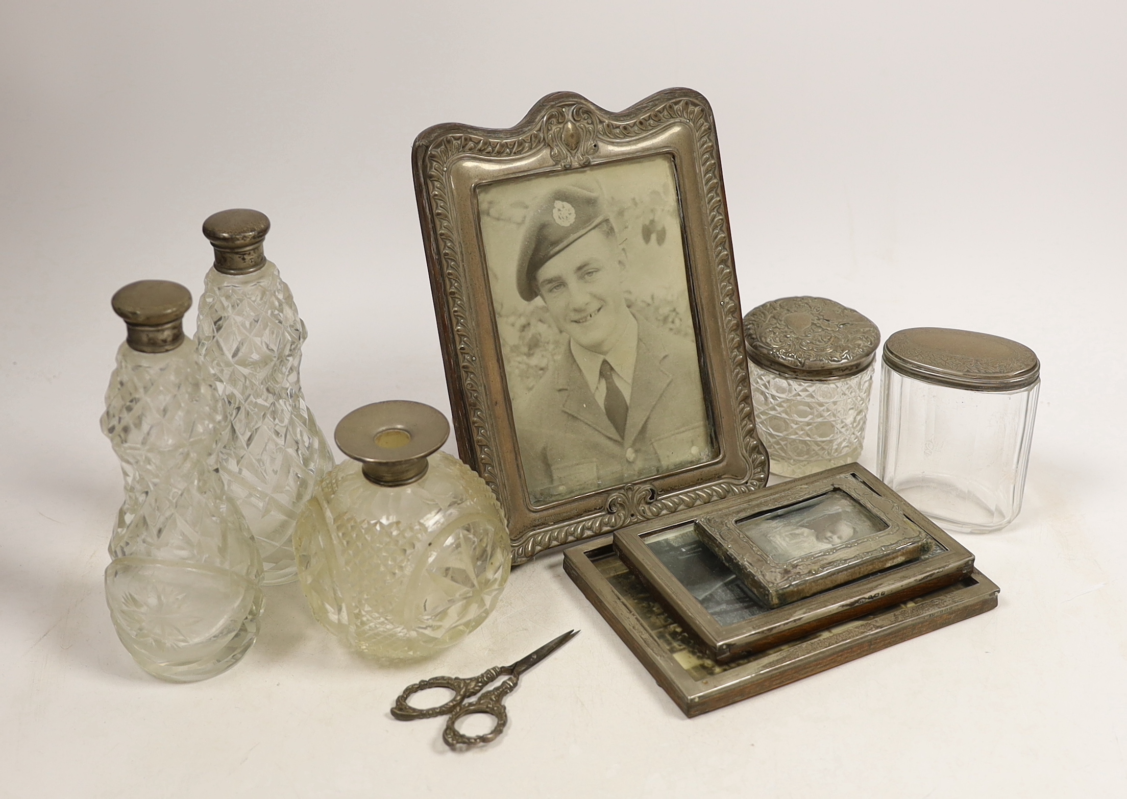 Four assorted early 20th century silver mounted photograph frames, largest 19.5cm (a.f.) five assorted silver mounted glass toilet jars and a small pair of silver handled scissors.